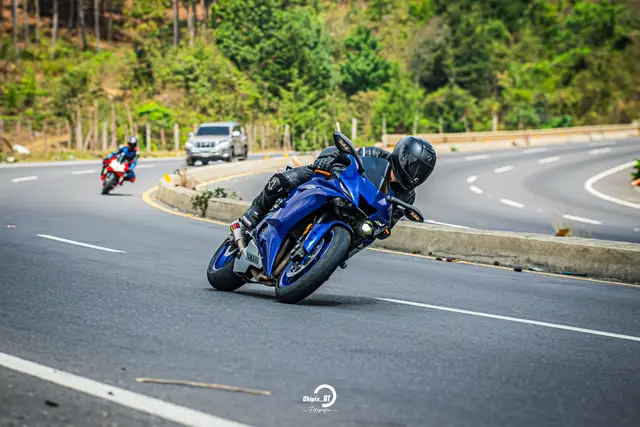 Riding a blue Yamaha sport bike through a mountain curve, leaning into the turn