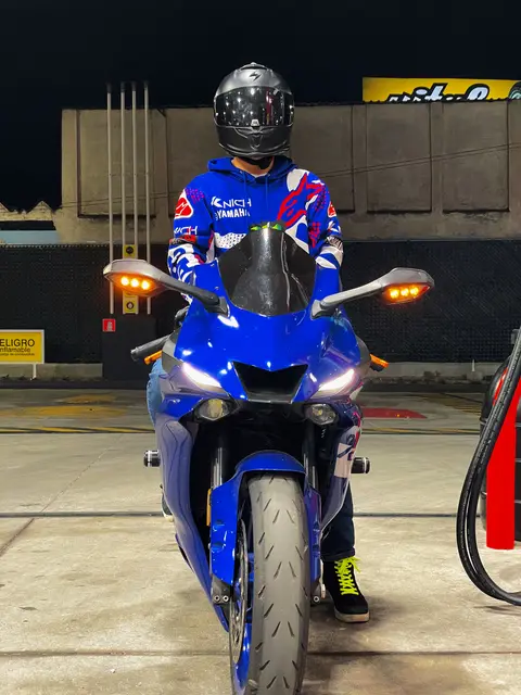 The bike head-on at night, rider in a helmet behind the handlebars