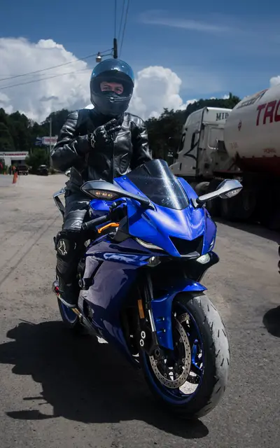 Standing beside the bike in a helmet and leather jacket on a sunny road