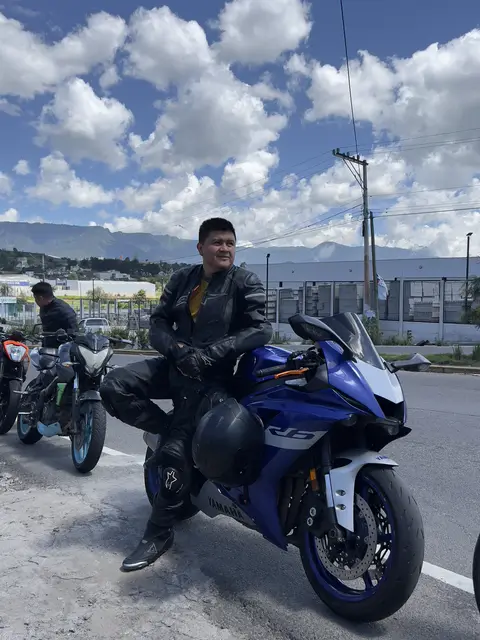 Sitting on the blue Yamaha in riding gear under a sky full of clouds
